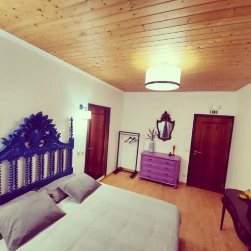 Quarto moderno na SOTAM Country House com cômoda roxa, teto de madeira, paredes brancas e portas vermelhas com vista para o jardim