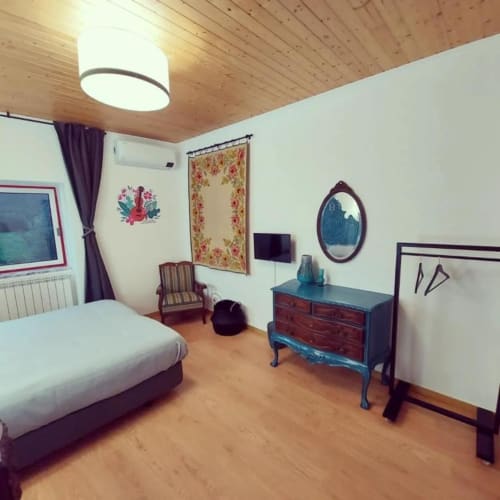Quarto 3 da Casa Rural SOTAM com teto em madeira, arte floral nas paredes, cómoda antiga e vista para o jardim em Góis, Portugal
