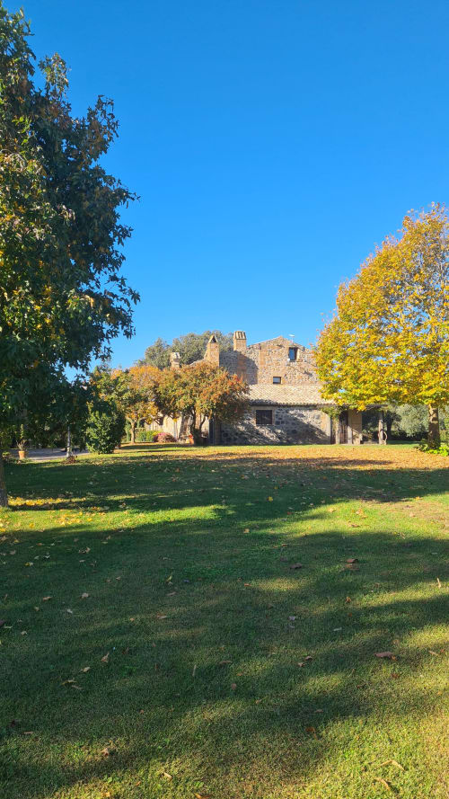 Casa colonica in pietra con terrazza circondata da alberi autunnali e giardino verde presso l'Agriturismo Buriano, Lubriano Italia
