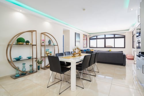 Modern Marbella apartment dining area with turquoise ceiling, white table, black chairs, and decorative shelving