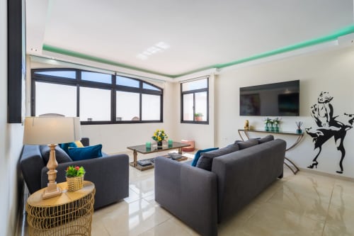 Modern living room in Marbella beachfront apartment with gray sofas, TV, floor-to-floor windows, and contemporary decor