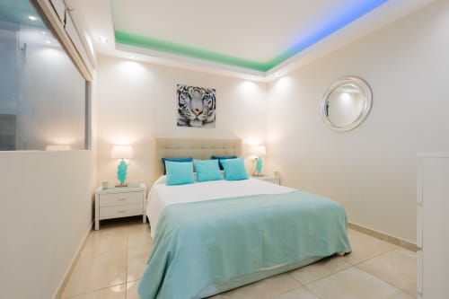 Modern bedroom at Marbella beachfront apartment with turquoise bedding, white headboard, contemporary lighting, and tiger