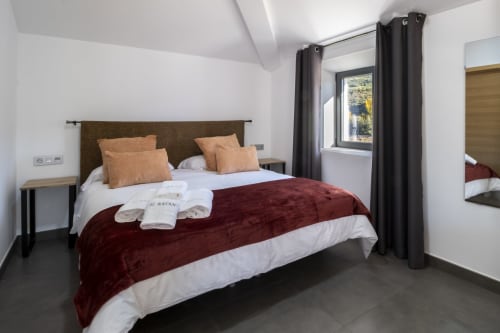 Suite Principal del Hotel Spa El Batán en Castillo de Locubín con cama burdeos, almohadas de terracota y vistas al monumento