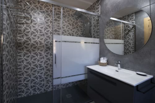 Baño moderno del Hotel Spa El Batán con paredes de azulejos con patrón, ducha de cristal y lavabo blanco