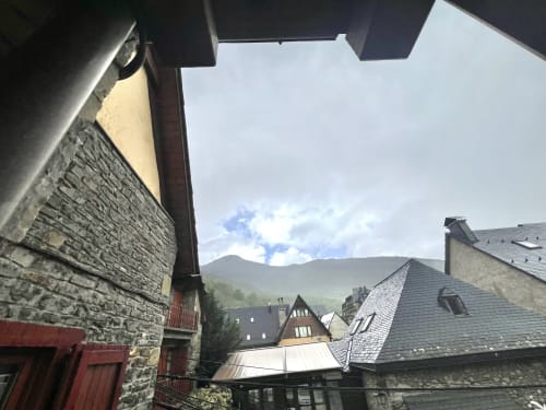 Vista de montaña desde el patio de un edificio de piedra en Vielha, Pirineos, mostrando arquitectura tradicional y paisaje de cimas