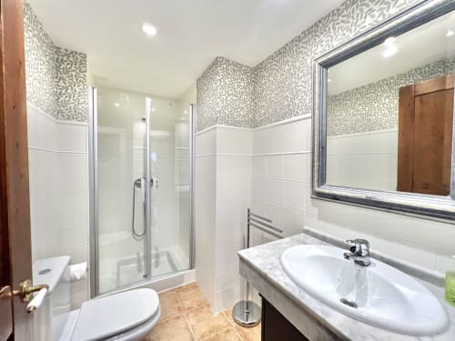 Baño moderno en apartamento Era Clau Homes con azulejos metro blancos, papel tapiz estampado, cabina de ducha acristalada y marcos