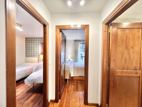 Pasillo con puertas de madera que abren a los dormitorios del apartamento Era Clau Homes en Vielha, España