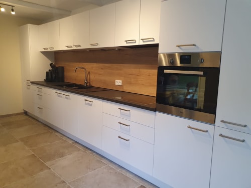 Cuisine blanche moderne avec dosseret en bois, four en acier inoxydable et plan de travail foncé au Sur La Rive Vierre B&B à Chiny