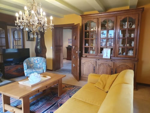 Élégant salon de la Sur La Rive Vierre B&B à Chiny avec canapé jaune, lustre et meuble en bois