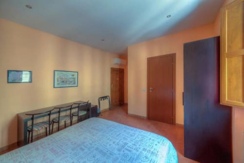 Spacious double room with single beds at Sogni D'Oro Guest House in Florence, featuring warm orange walls, wooden furniture,