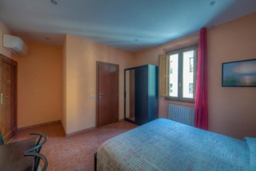 Spacious double room at Sogni D'Oro Guest House in Florence with twin beds, orange walls, blue ceiling, and city views