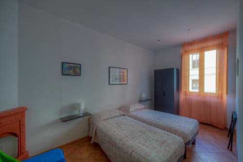 Camera doppia luminosa con due letti singoli, dettagli arancioni e vista sulla città presso la Sogni D'Oro Guest House a Firenze
