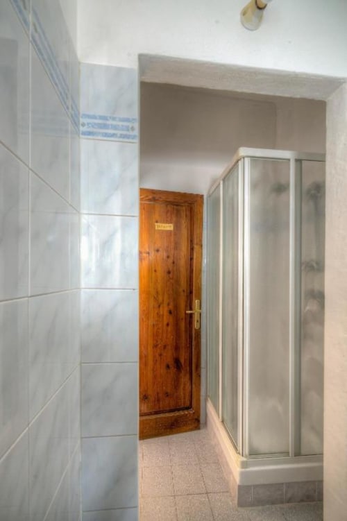 Corridoio del bagno condiviso presso la Guest House Sogni D'Oro di Firenze, con pareti in piastrelle bianche e cabina doccia in vetro satinato
