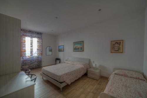 Luminosa camera quadrupla presso la Sogni D'Oro Guest House di Firenze con due letti, pavimenti in legno, opere d'arte incorniciate e vista sulla città