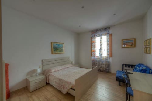 Camera quadrupla luminosa a Sogni D'Oro Guest House di Firenze con pavimento in legno, letto color crema e tende decorate