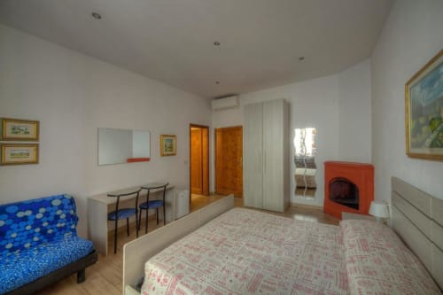 Ampia quadrupla alla Sogni D'Oro Guest House di Firenze con camino, angolo cottura, letto, divano e pavimento in legno.