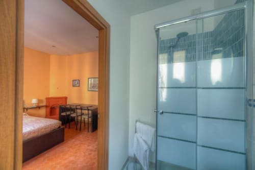 Sogni D'Oro guest house double room in Florence with two beds, glass shower enclosure, and city view through doorway