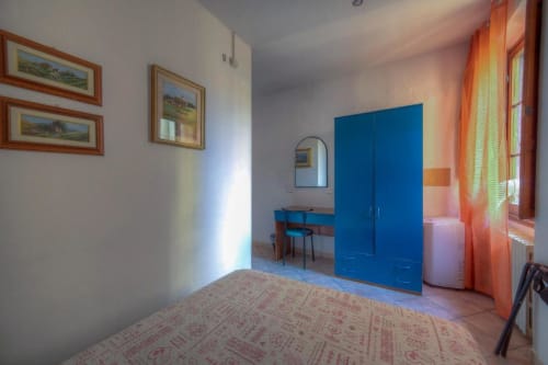 Luminosa camera doppia della Sogni D'Oro Guest House a Firenze con guardaroba blu, scrivania e vista sulla città attraverso tende arancioni