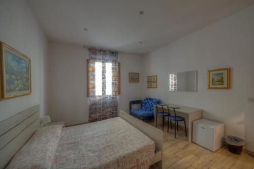 Camera luminosa con quattro letti presso la Sogni D'Oro Guest House di Firenze, con angolo cucina, scrivania e quadri alle pareti