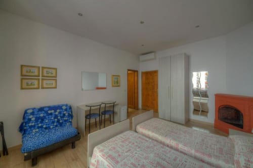 Spaziosa camera quadrupla presso la Sogni D'Oro Guest House a Firenze con letti, camino, angolo cottura e vista sulla città