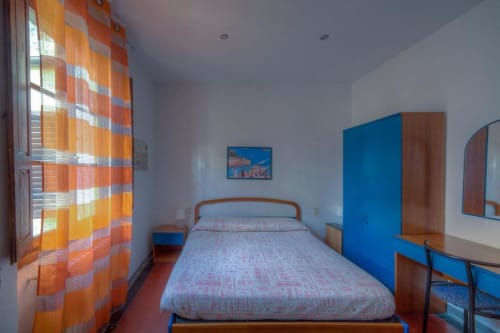Luminosa camera matrimoniale alla Sogni D'Oro Guest House di Firenze con armadio blu, letto in legno, scrivania e plaid arancione