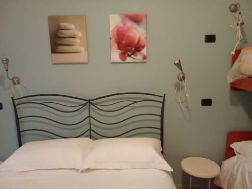 Camera da letto con testata ondulata in metallo, cuscini bianchi, quadri e mensole decorative nell'appartamento My Home Rapallo a Rho, Italia