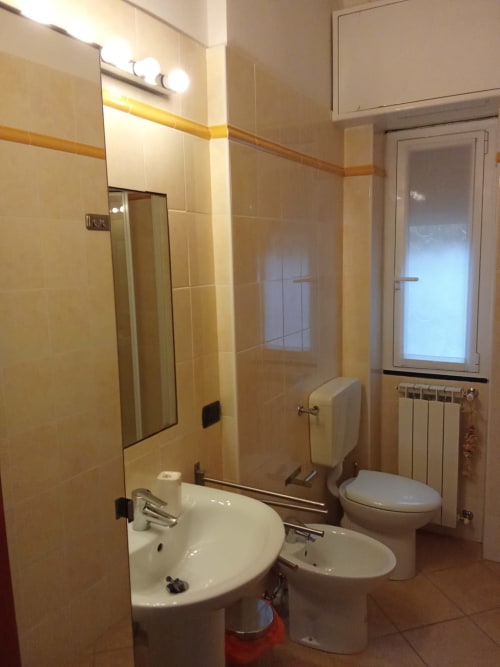 Bagno moderno dell'appartamento My Home Rapallo a Rho con piastrelle, lavabo, toilette e specchio illuminato