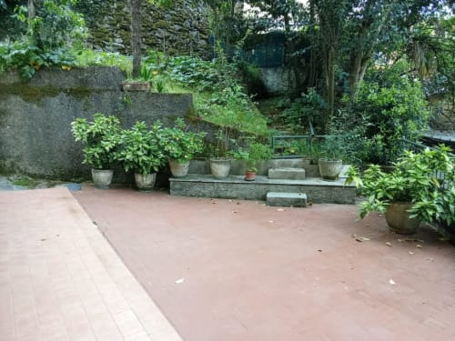 Splendido patio fiorito dell'appartamento My Home Rapallo a Rho con piante in vaso, pavimento in terracotta e lussureggiante vegetazione