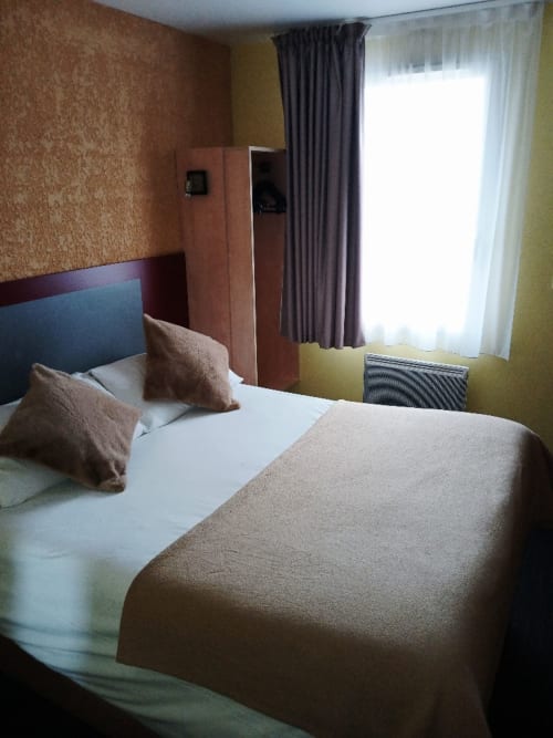 Chambre spacieuse quadruple au Libre Hôtel avec lits jumeaux, literie beige, armoire moderne et vue sur le jardin