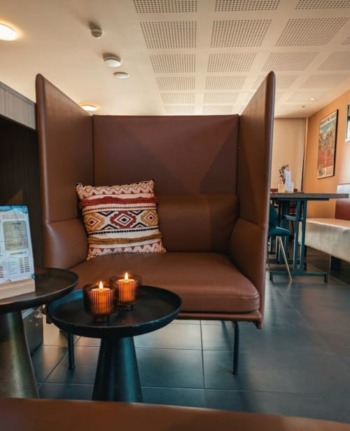 Banquette en cuir marron avec coussin décoratif au salon de l'hôtel La Verriaire, France
