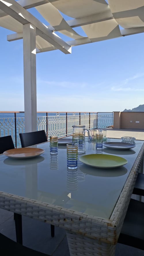 Tavolo da pranzo con vista mare e pergolato all'aperto presso l'appartamento Gold Leaf Sicily Taormina
