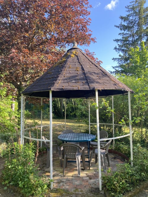 Conical-roofed garden gazebo with dining table and chairs at Les Gîtes de l'Impériale, Sermizelles, surrounded by autumn