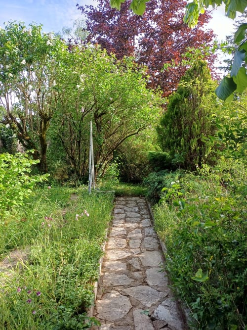 Allée de jardin en pierre envahie de végétation luxuriante aux Gîtes de l'Impériale à Sermizelles