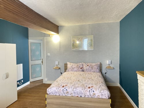 Chambre moderne aux Les Gîtes de l'Impériale à Sermizelles avec murs accentués turquoise, lit en bois et vue sur jardin