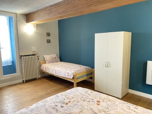 Chambre lumineuse aux Gîtes de l'Impériale à Sermizelles avec lits jumeaux, mur d'accent bleu-vert et armoire en bois