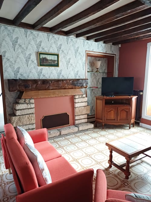 Séjour douillet aux Gîtes de l'Impériale avec fauteuils rouges, cheminée, TV et poutres apparentes