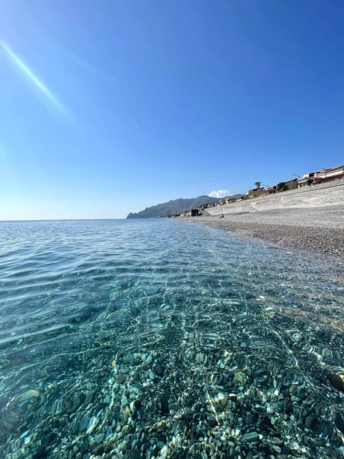 Acque turchesi cristalline sulla spiaggia privata di Gold Leaf Sicily a Taormina con scogliere costiere