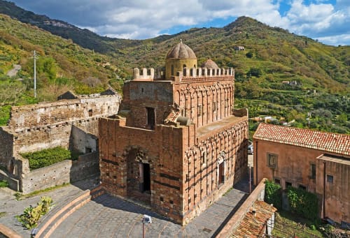 Storica moschea di Taormina con cupola dorata circondata da rigogliose colline siciliane e muri antichi