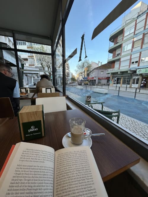 Espaço de leitura no café da pousada Vila Alexandra em Costa da Caparica com vista para a praça e café