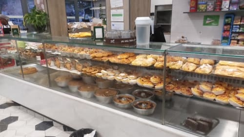 Vitrine da padaria na pousada Vila Alexandra em Costa da Caparica com pastéis frescos, pães e produtos de confeitaria atrás do vidro.