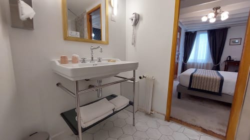 Bagno moderno dell'Hotel Dandy Rouen con lavabo su piedistallo, specchio e vista sulla camera con letto matrimoniale