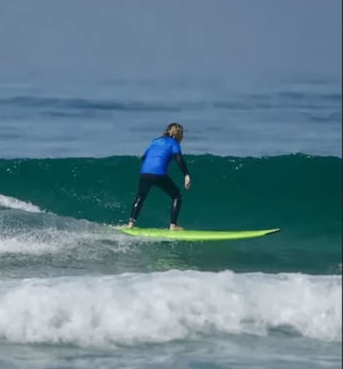 Surfista em fato de banho azul surfando uma onda na praia da Costa da Caparica perto do hostel Vila Alexandra