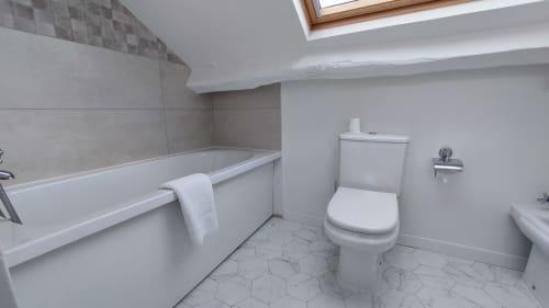 Bagno moderno dell'Hotel Dandy Rouen con vasca bianca, toilette e piastrelle esagonali