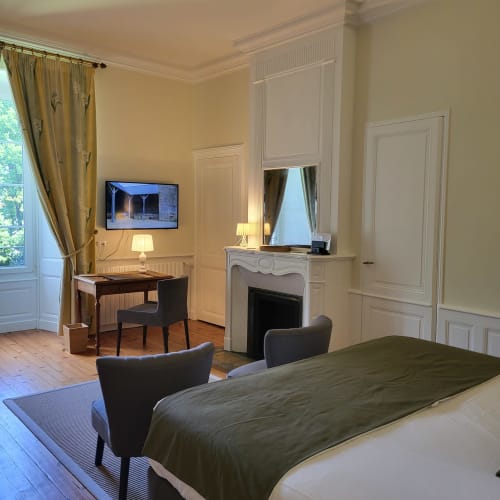 Chambre élégante aux Logis des Tourelles, Cognac avec lit, cheminée, bureau, TV et vue sur le jardin
