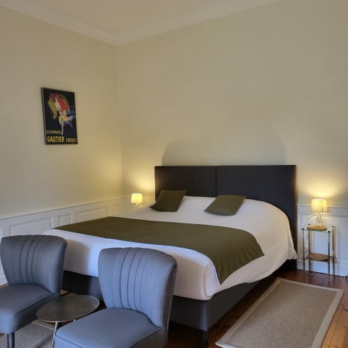 Chambre élégante au Logis des Tourelles à Cognac avec lit king-size, vue sur le jardin, mobilier moderne et cognac vintage