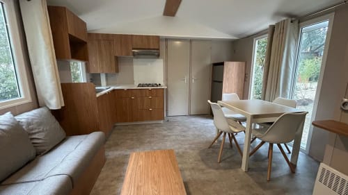Intérieur moderne de mobil-home au Camping La Lézardière avec cuisine, table à manger et vue sur le jardin