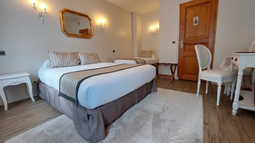 Spacieuse chambre triple à l'Hôtel Dandy Rouen avec lit queen-size, literie rayée, miroir doré et mobilier moderne