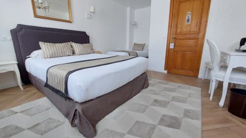 Camera tripla dell'Hotel Dandy Rouen con letto dalla testata viola, biancheria a righe, arredamento bianco, porta in legno e motivi decorativi