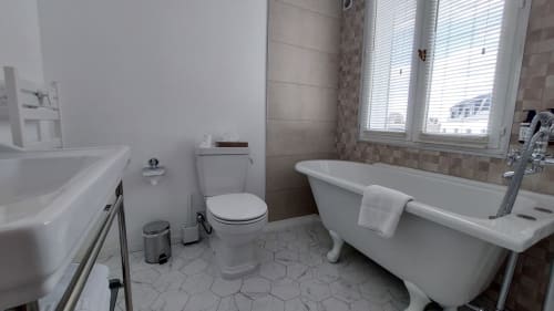 Bagno moderno dell'Hotel Dandy a Rouen con vasca freestanding, wc, lavabo e piastrelle esagonali