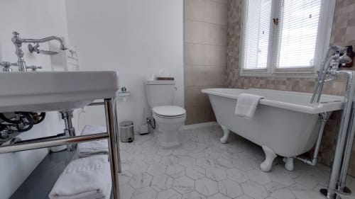 Bagno lussuoso dell'Hotel Dandy a Rouen con vasca indipendente, lavabo su piedistallo e pavimentazione con piastrelle esagonali